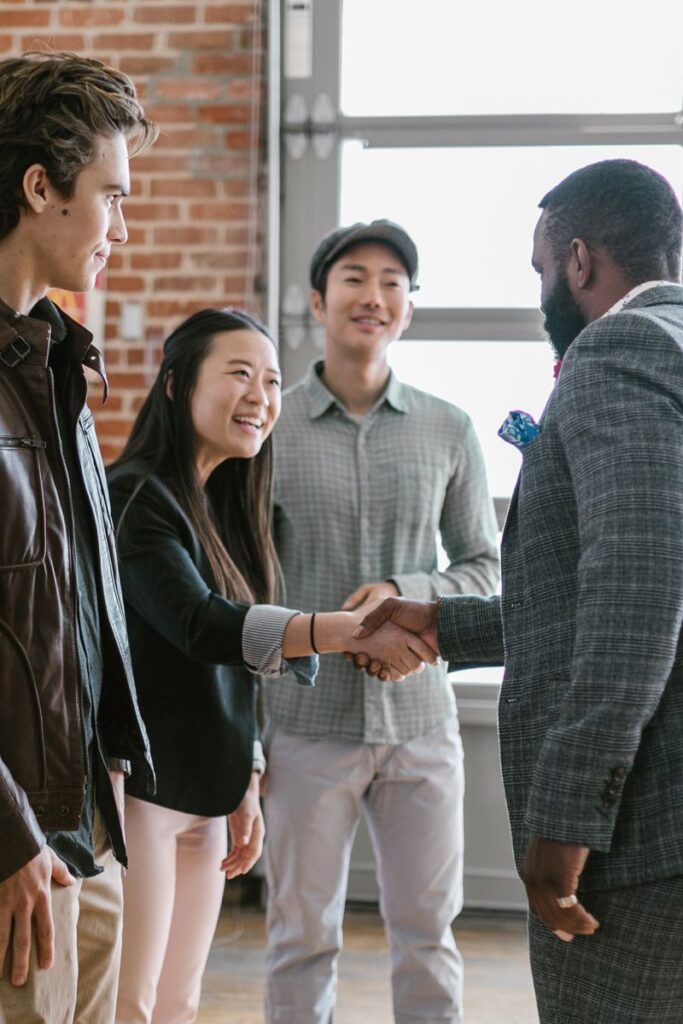 A diverse group of business professionals engaging in a handshake and discussion in a modern office space.